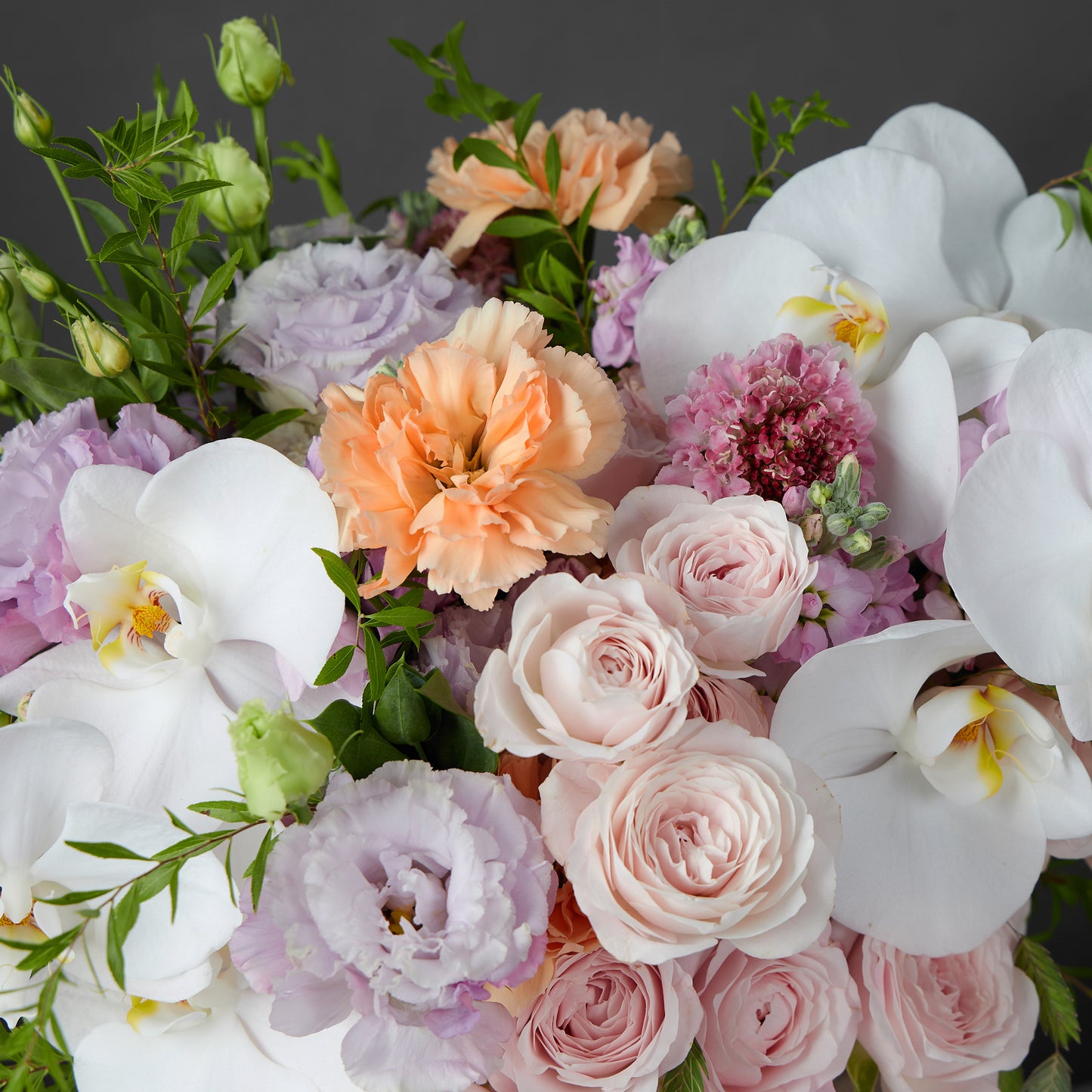 soft pink spray roses, orange carnation, white orchid, purple eustoma